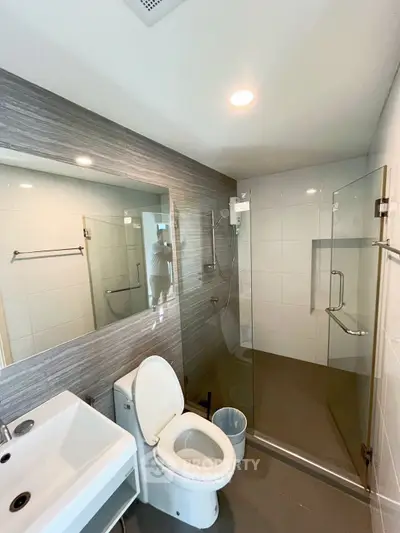 Modern bathroom with glass shower and sleek fixtures in contemporary apartment.