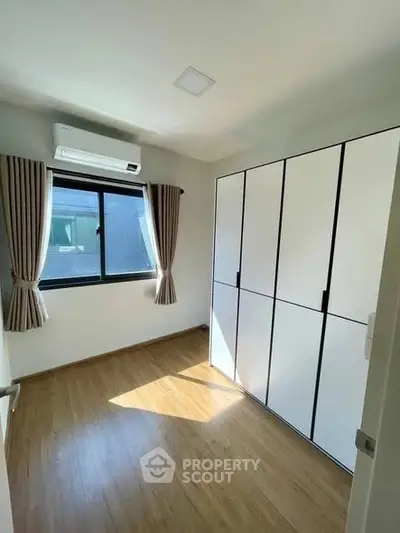 Bright bedroom with wooden flooring and large wardrobe