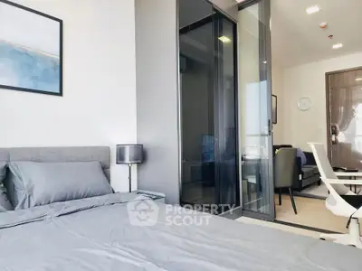 Modern bedroom with sleek design and glass partition leading to living area.