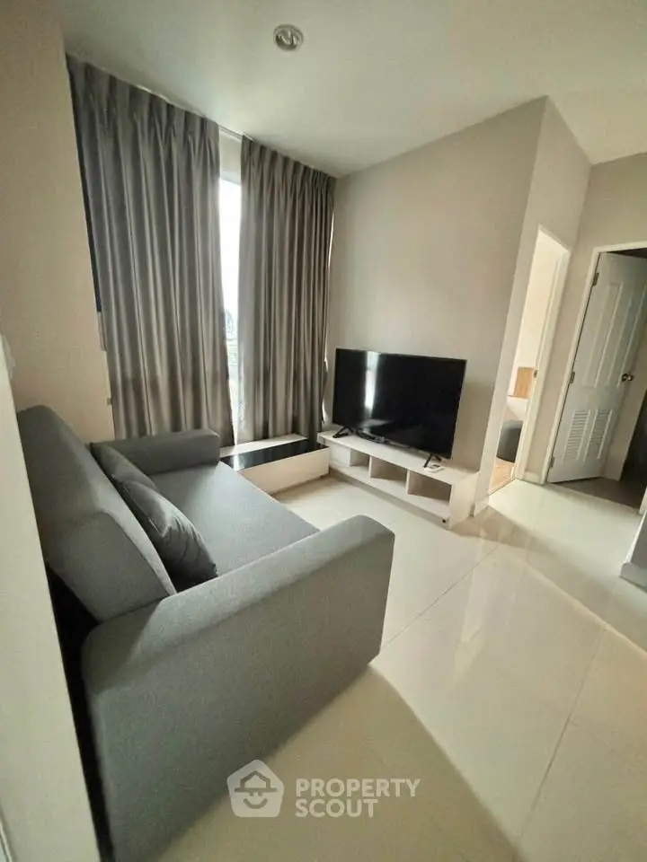 Modern living room with sleek gray sofa and large TV, perfect for relaxation and entertainment.