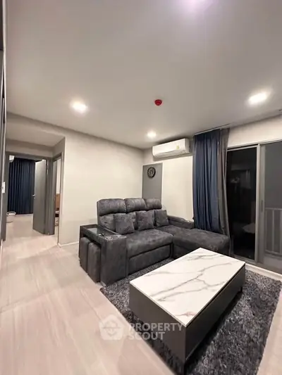 Modern living room with plush gray sofa, marble coffee table, and balcony access in a stylish apartment.