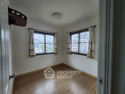 Bright empty room with wooden flooring and large windows, perfect for customization.