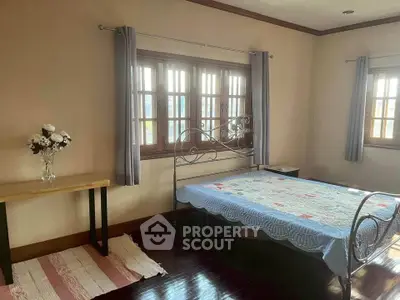 Cozy bedroom with elegant metal bedframe and natural light from large windows.