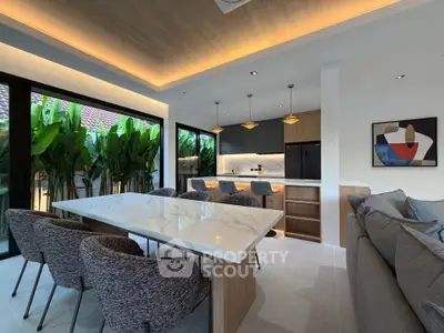 Luxurious open-plan living room with modern kitchen and elegant dining area, featuring stylish lighting and lush garden view.