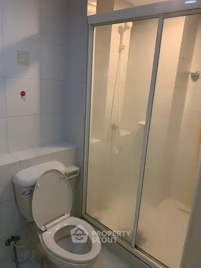 Compact bathroom with shower enclosure and toilet in modern apartment.