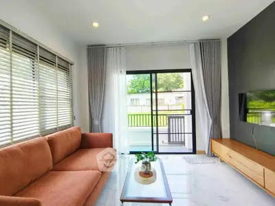 Modern living room with large windows and stylish furniture, offering a bright and inviting atmosphere.