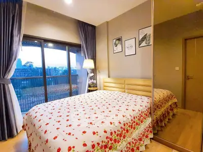 Cozy bedroom with floral bedding and mirrored wardrobe, offering a serene balcony view.