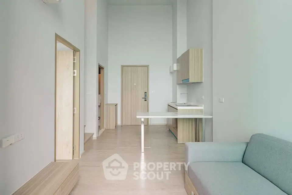 Modern minimalist apartment interior with high ceilings and sleek kitchen design.