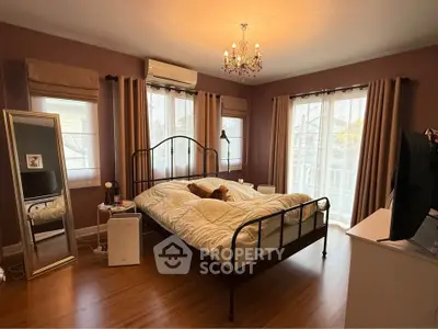 Cozy bedroom with elegant chandelier and large windows for natural light