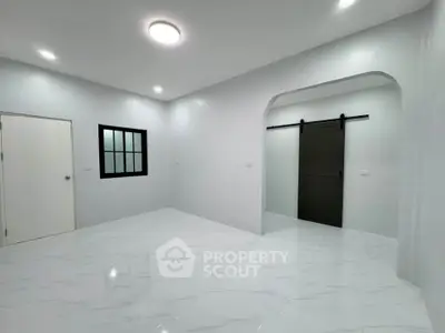 Spacious modern living room with sleek sliding barn door and elegant white flooring.