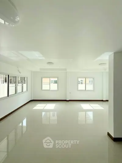 Spacious and bright living room with large windows and glossy tiled floors, perfect for modern living.