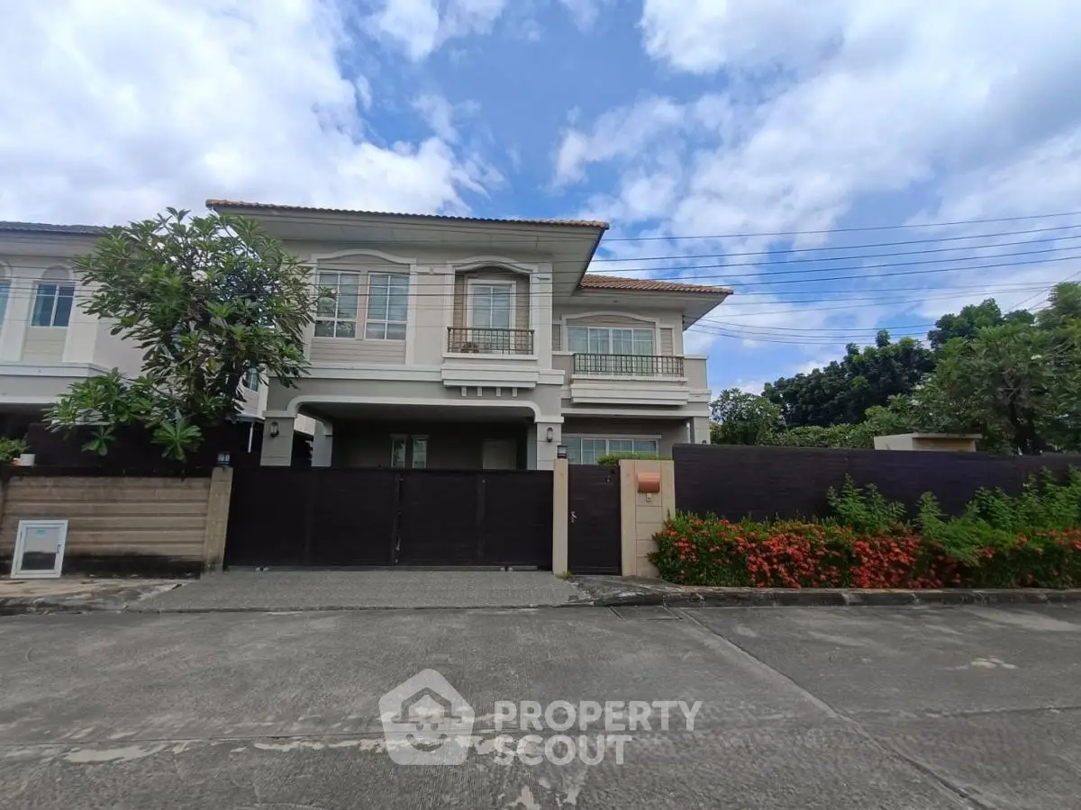 Elegant two-story house with lush garden and secure gated entrance in a serene neighborhood.