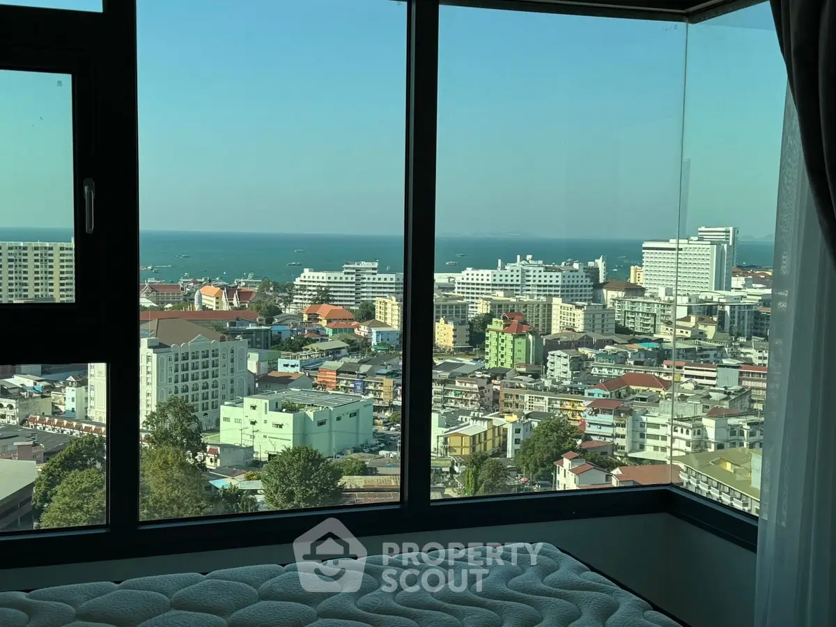 Stunning cityscape view from a high-rise apartment window overlooking the ocean.