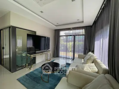 Luxurious living room with modern decor, large TV, and floor-to-ceiling windows overlooking a garden.