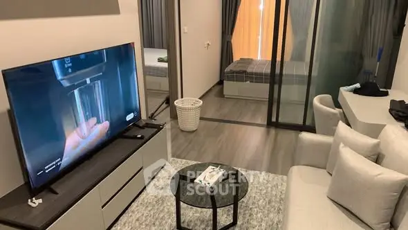 Modern living room with sleek furniture and a view into a cozy bedroom through glass doors.