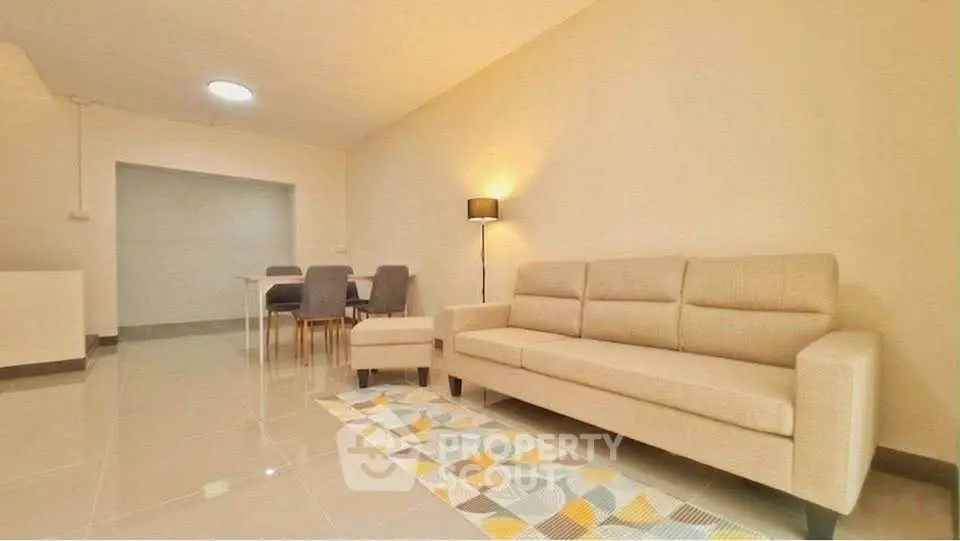 Spacious living room with modern beige sofa and dining area, perfect for family gatherings.