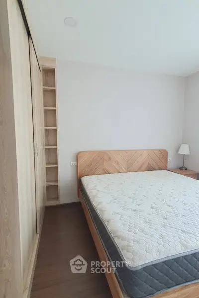 Spacious bedroom with wooden flooring and modern furnishings, featuring a large bed and built-in wardrobe.