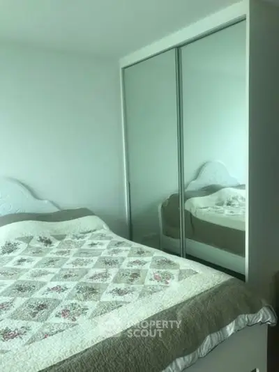 Cozy bedroom with mirrored wardrobe and elegant quilted bedspread.