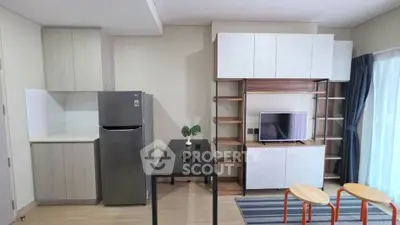 Modern living room with sleek furniture and open kitchen layout, featuring a stylish TV unit and natural light.