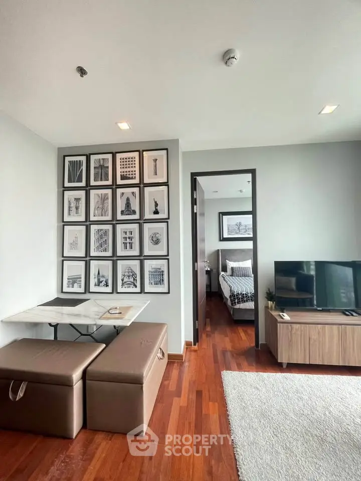 Modern living room with stylish decor and bedroom view, featuring hardwood floors and a cozy seating area.