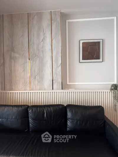 Elegant living room with black leather sofa and modern wall art