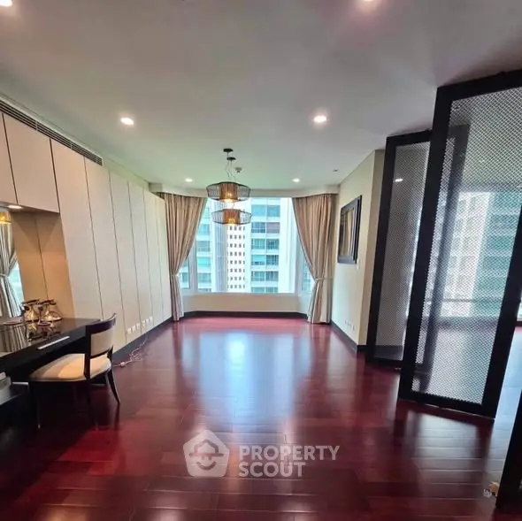 Spacious living room with hardwood floors and large windows offering city views.