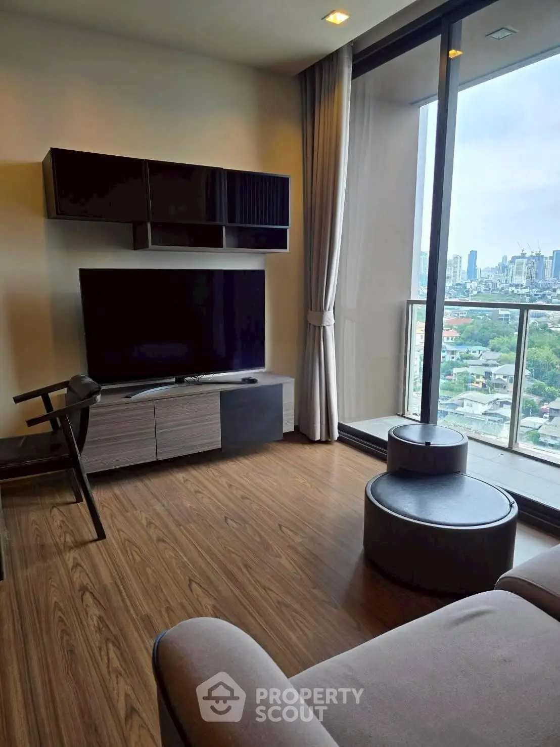 Modern living room with large TV and city view from balcony