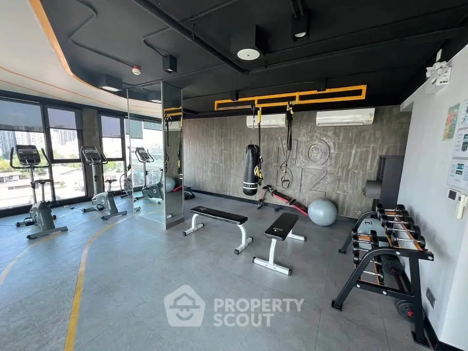 Modern gym with fitness equipment and city view in luxury apartment building.