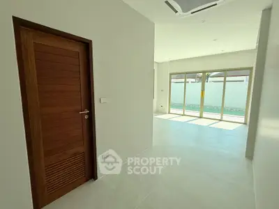 Spacious modern interior with large windows and wooden door, perfect for natural light lovers.
