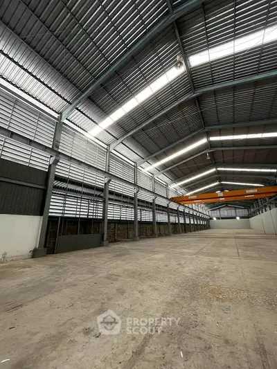Spacious industrial warehouse with high ceilings and ample natural light, perfect for storage or manufacturing.