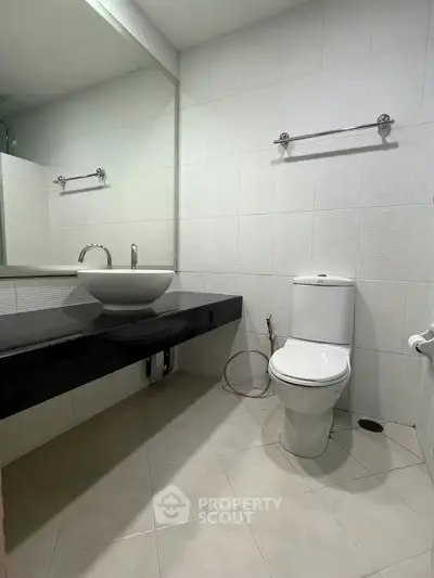 Modern bathroom with sleek fixtures and minimalist design, featuring a large mirror and elegant sink.