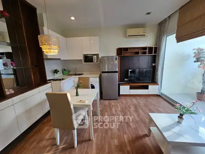 Modern open-plan living room with kitchen, featuring sleek furniture and large window for natural light.