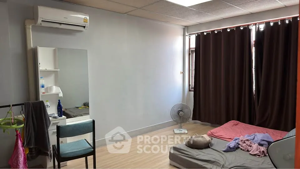 Cozy bedroom with minimalist decor, featuring a bed, chair, and air conditioning unit.
