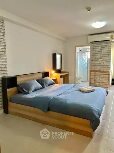 Spacious bedroom with modern decor and ensuite bathroom in a stylish apartment.