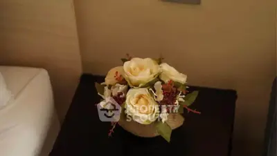 Elegant floral arrangement on a bedside table in a cozy bedroom setting.