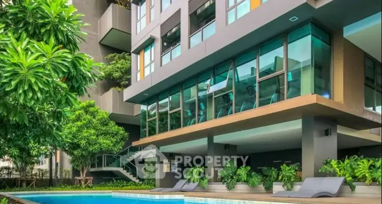 Modern apartment building with pool and lush greenery