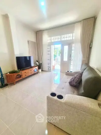 Spacious living room with modern decor and natural light, featuring a comfortable sofa and entertainment center.
