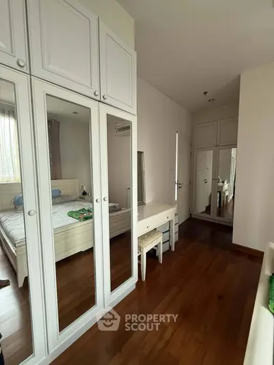 Spacious bedroom with mirrored wardrobes and wooden flooring