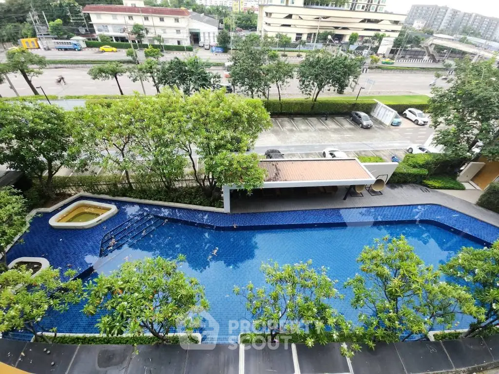 Stunning aerial view of a luxurious swimming pool surrounded by lush greenery in a modern residential complex.