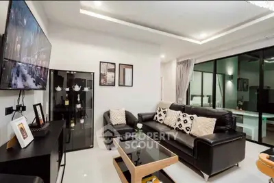 Modern living room with sleek black leather sofa and glass coffee table