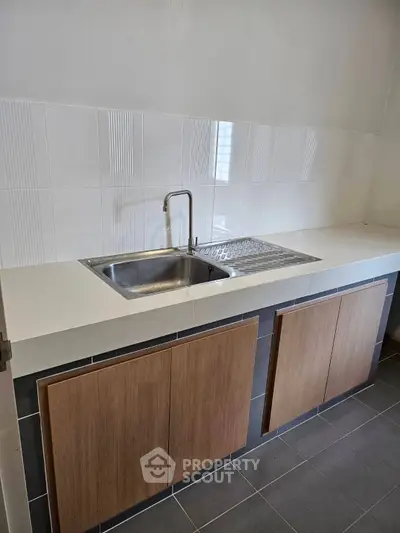 Modern kitchen with sleek cabinetry and stainless steel sink in minimalist design.