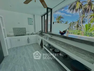 Stunning kitchen with open layout and tropical view, featuring modern countertops and ample storage space.