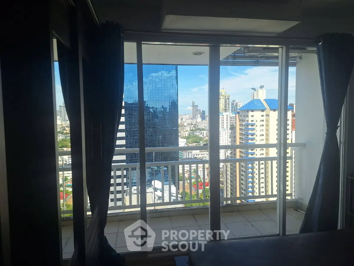 Stunning city view from high-rise apartment balcony with glass doors.