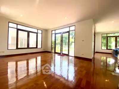 Spacious living room with polished wooden floors and large windows offering natural light.