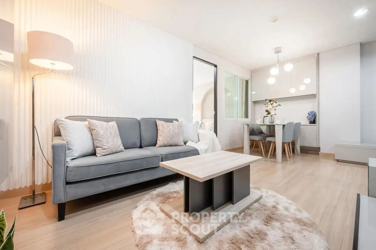 Modern living room with cozy decor and dining area, featuring elegant lighting and stylish furniture.