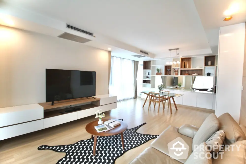 Spacious modern living room with stylish decor and large TV, perfect for relaxation and entertainment.