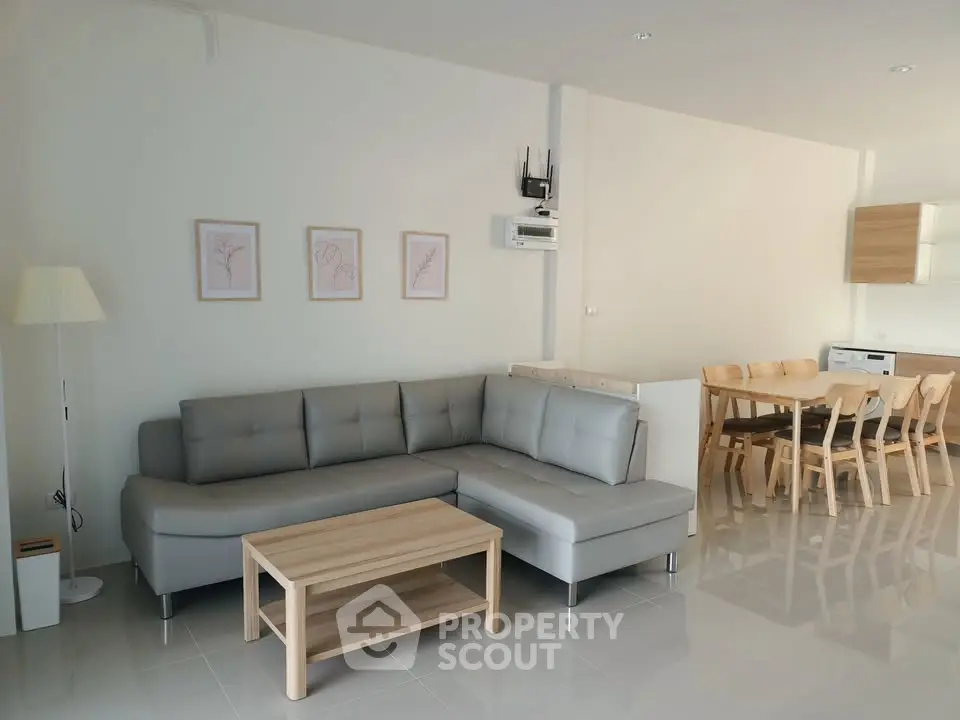 Modern living room with sleek gray sofa and dining area, perfect for contemporary living.