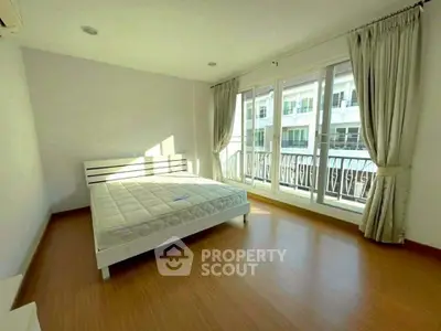 Spacious bedroom with large windows and balcony access in modern apartment.