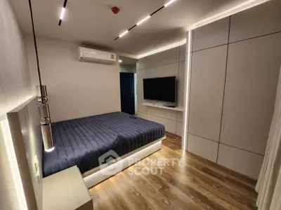 Modern bedroom with sleek design, featuring a wall-mounted TV and ambient lighting.