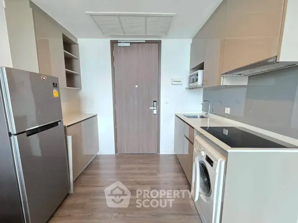 Modern kitchen with sleek cabinetry, integrated appliances, and wood flooring in a contemporary apartment.